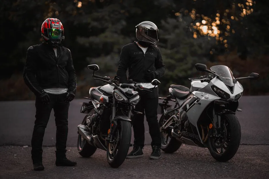 Débutant en équipement posant à côté d'une moto légère dans une cour, casque sous le bras
